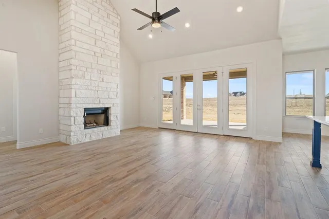 an empty room with wooden floor fireplace and windows