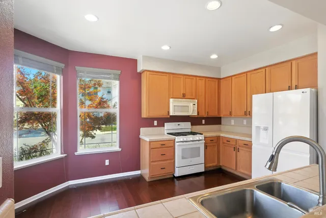 a kitchen with a sink a stove a refrigerator and white cabinets