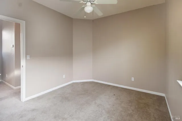 an empty room with a chandelier fan and windows