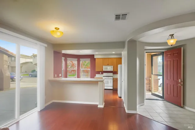 a view of an empty room with wooden floor fireplace and a window
