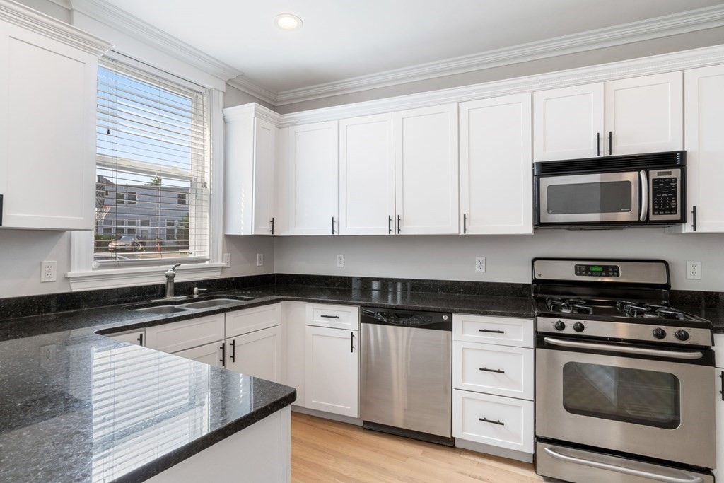 a kitchen with granite countertop white cabinets and appliances