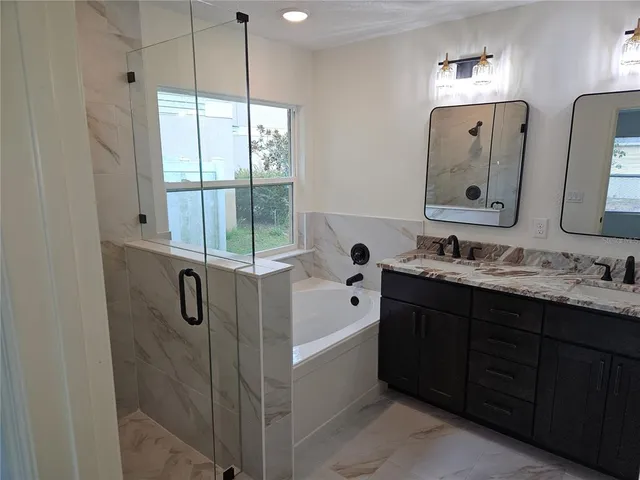 a bathroom with a double vanity sink and mirror with bathtub