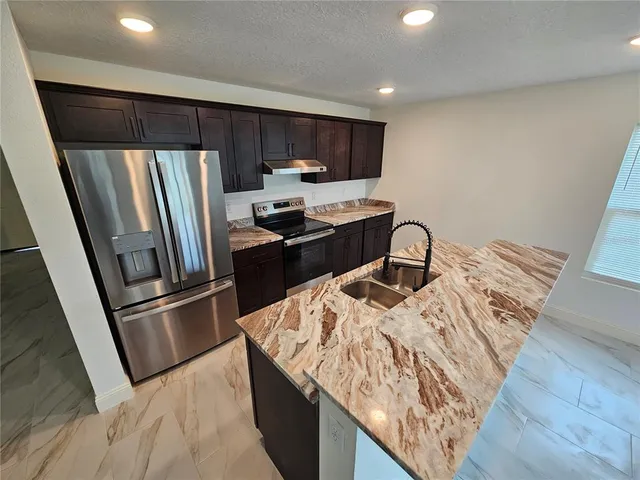 a kitchen with stainless steel appliances granite countertop a refrigerator a stove a sink and a microwave