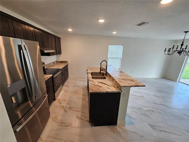 a kitchen with granite countertop a refrigerator and a sink