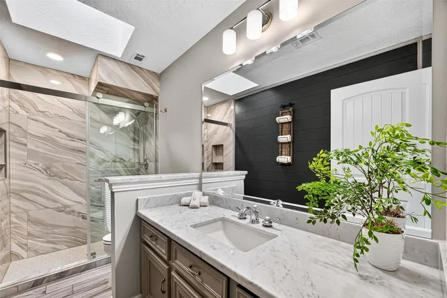 a bathroom with a granite countertop sink a large mirror and a shower