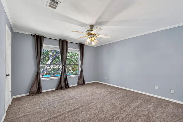 an empty room with windows and ceiling fan