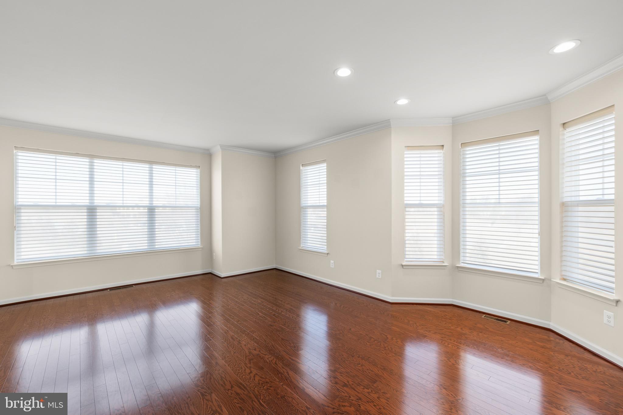 210 Flyfoot Drive Stephenson, VA 22656 - Photo 12 of 38 an empty room with wooden floor and windows with curtains view