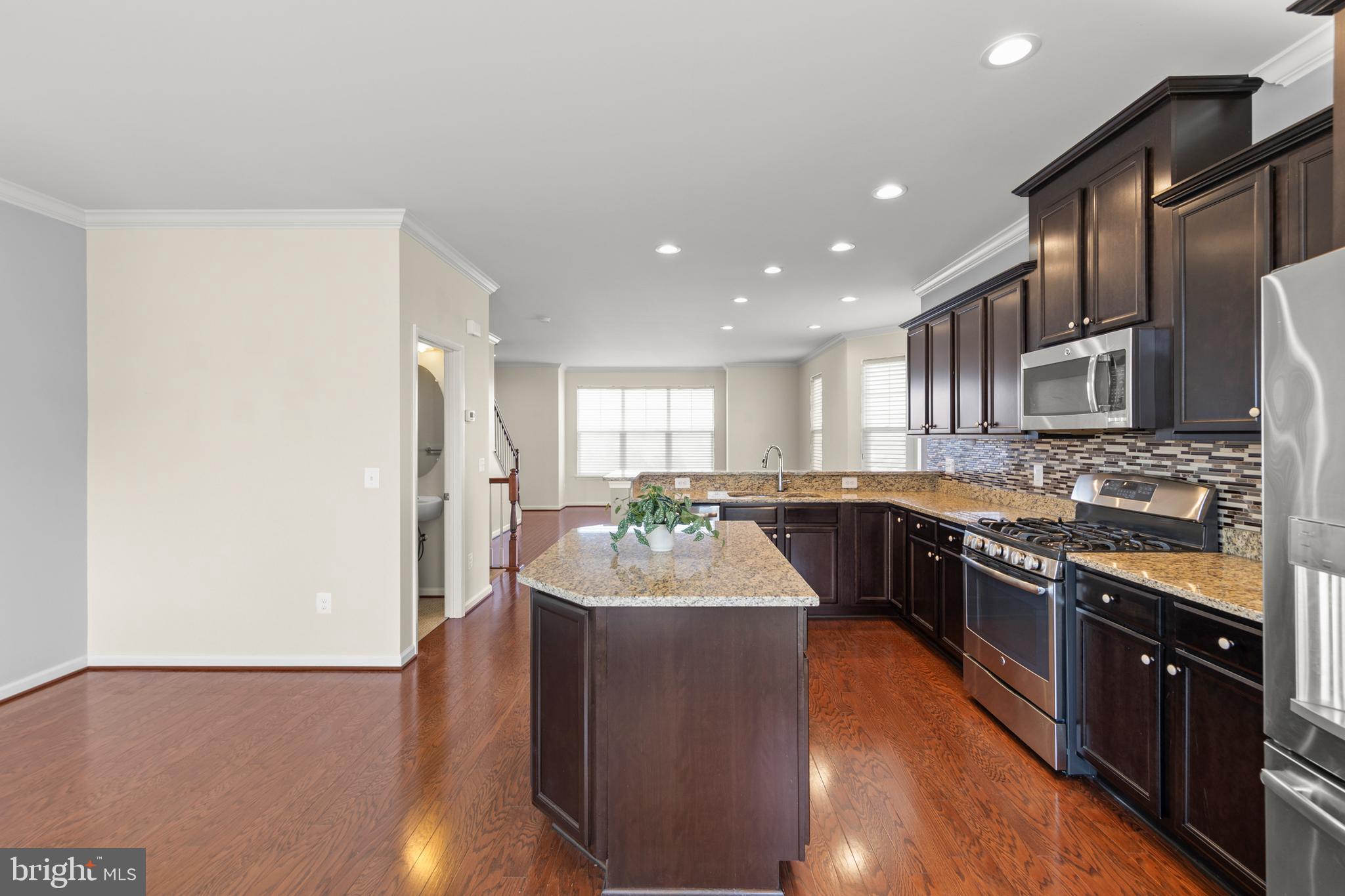 210 Flyfoot Drive Stephenson, VA 22656 - Photo 22 of 38 a large kitchen with stainless steel appliances a sink dishwasher a refrigerator a stove top oven and a dining table with wooden floor