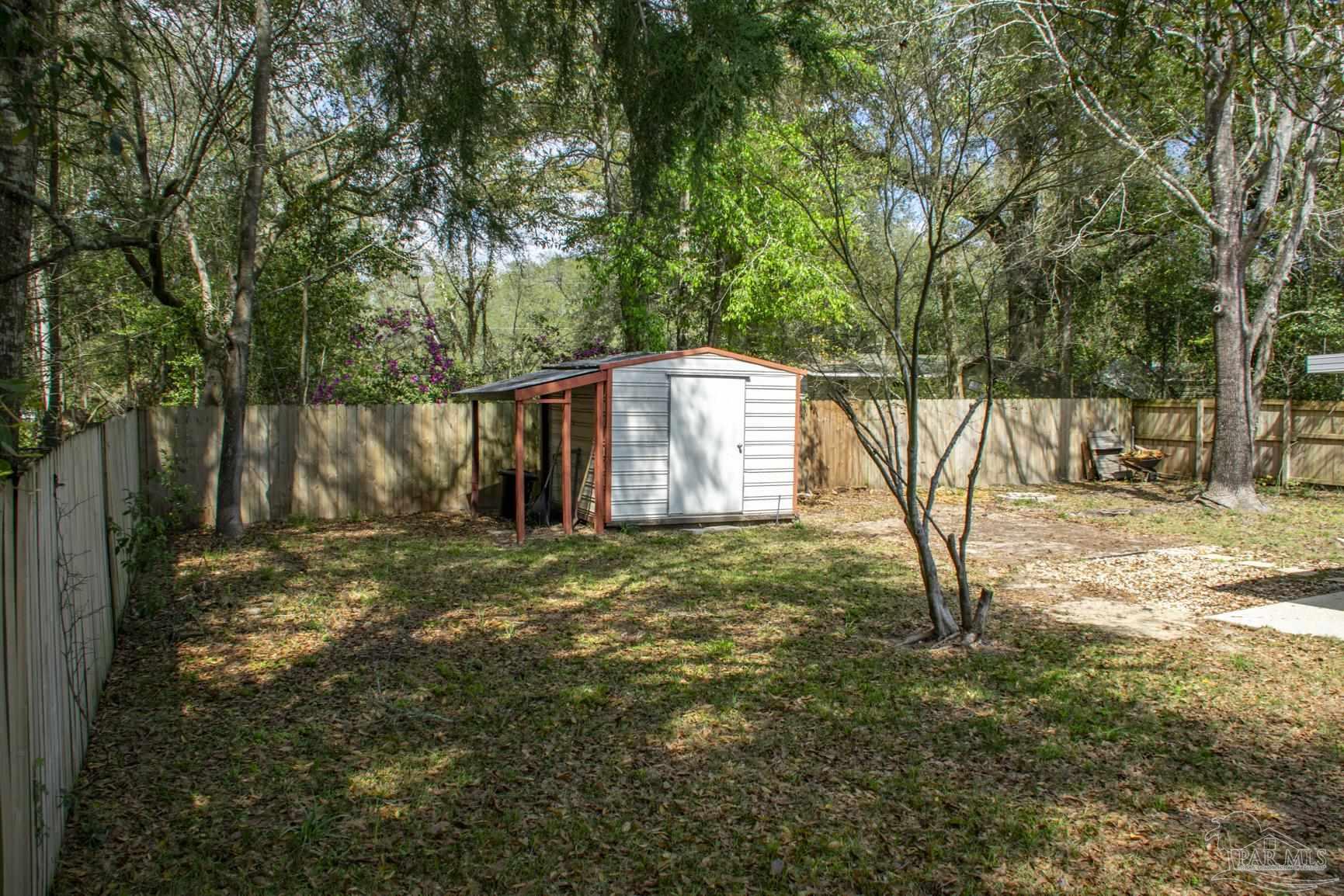 6514 Oakcrest Road Milton, FL 32570 - Photo 19 of 68 a backyard of a house with large trees and wooden fence