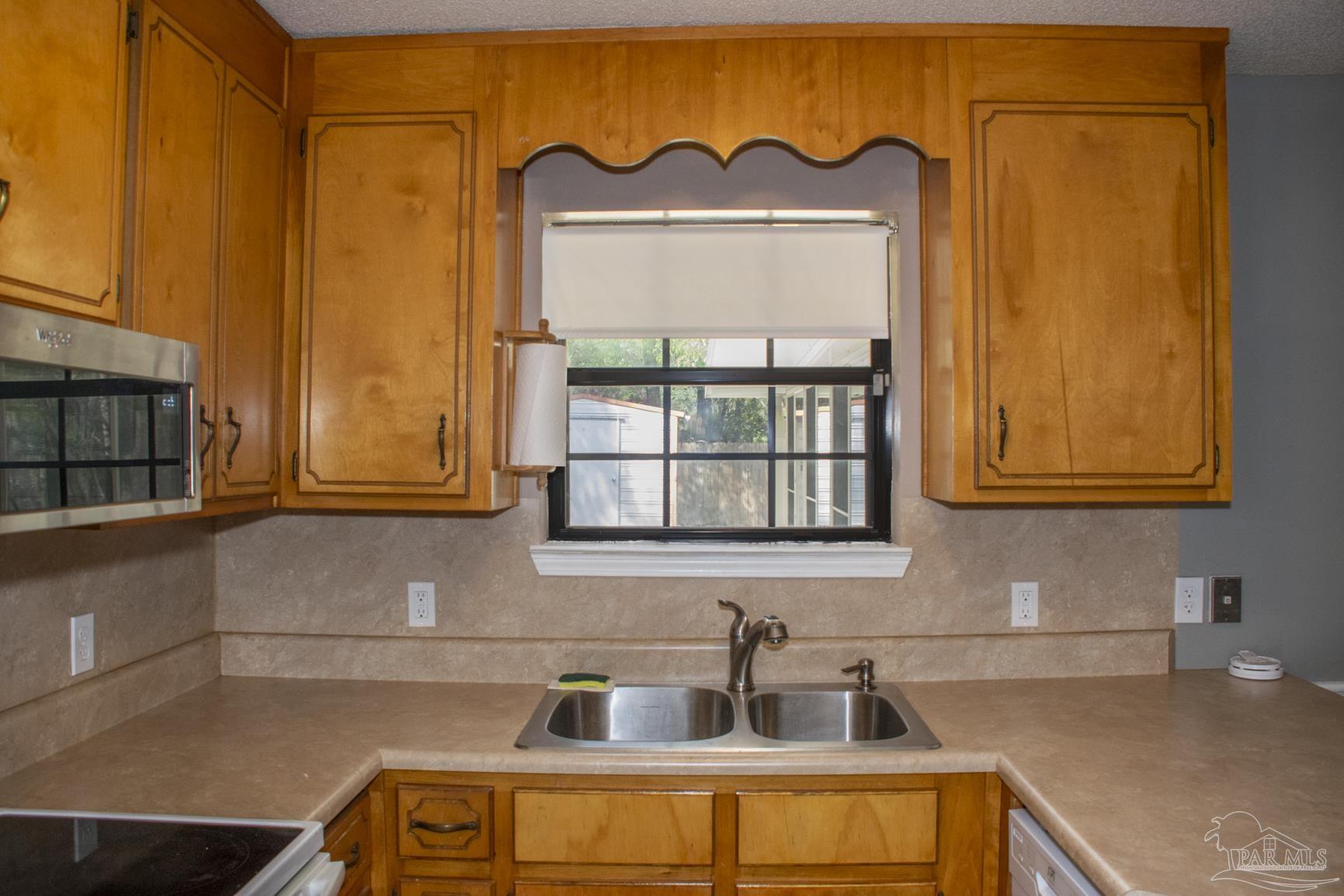 6514 Oakcrest Road Milton, FL 32570 - Photo 30 of 68 a kitchen with a sink a cabinets and a window