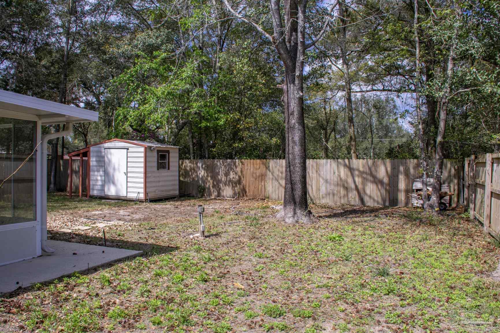 6514 Oakcrest Road Milton, FL 32570 - Photo 8 of 68 a view of a backyard with a tree and a bed