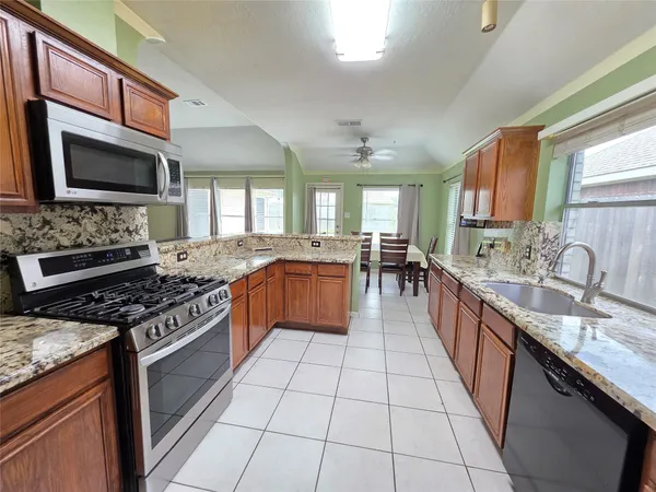 a large kitchen with stainless steel appliances granite countertop a stove top oven a sink dishwasher a dining table and chairs