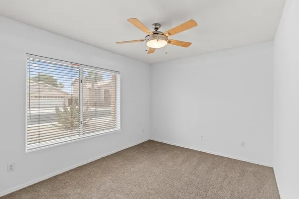 an empty room with a ceiling fan and window