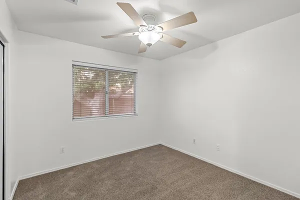 an empty room with a chandelier fan and windows