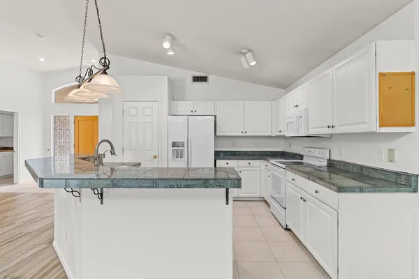a kitchen with kitchen island granite countertop a stove a sink a center island and cabinets