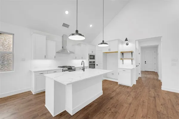 a view of a kitchen with kitchen island stainless steel appliances a center island and a wooden floors