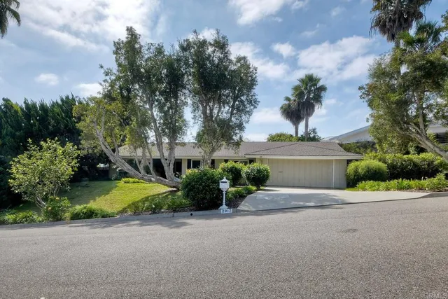 a front view of a house with a garden and trees