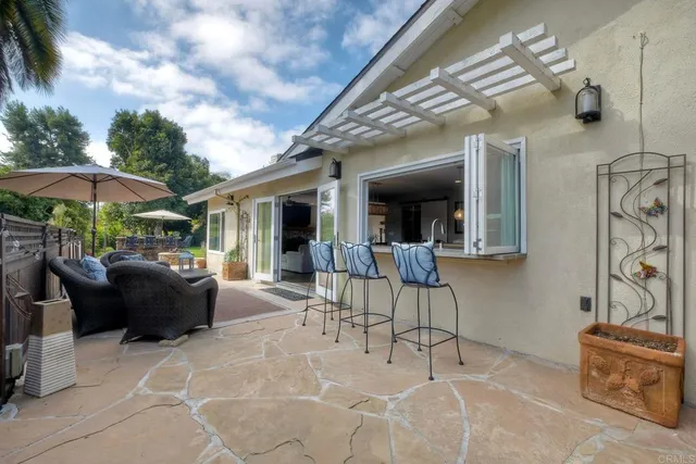 a view of a patio with table and chairs under an umbrella with a barbeque grill and couches