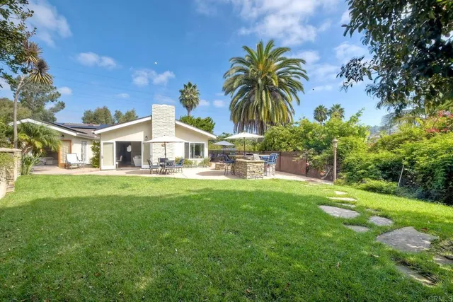 a view of a house with a big yard and palm trees