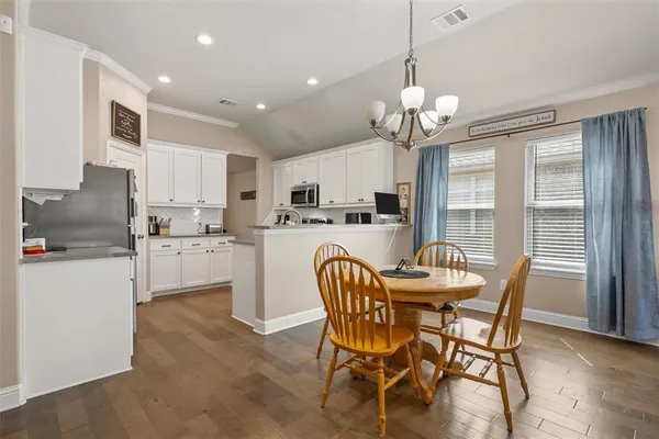 a dining room filled chandelier and kitchen view