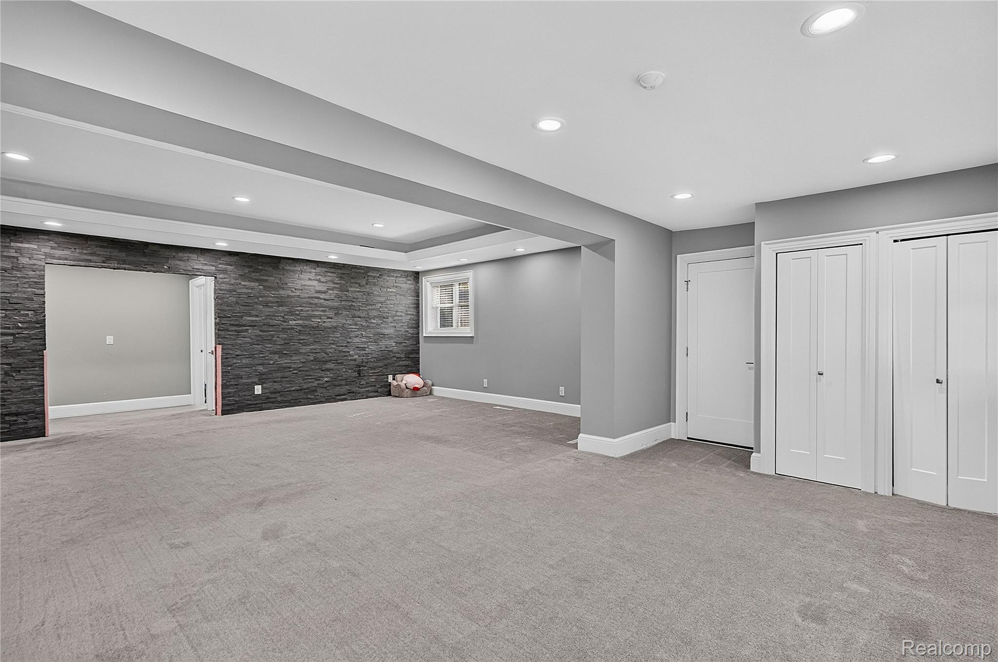 15879 Millar Road Clinton Township, MI 48036 - Photo 17 of 65 Spacious room featuring a stone accent wall, recessed lighting, crown molding, and two bi-fold closet doors