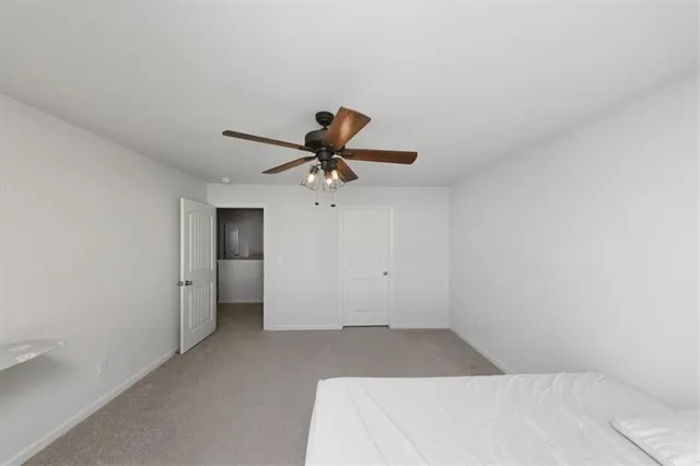 a view of a room with a ceiling fan and carpet