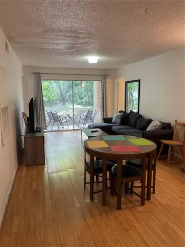a living room with furniture a table wooden floor and a large window