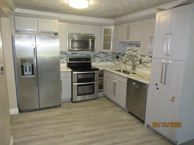 a kitchen with stainless steel appliances kitchen island granite countertop a refrigerator and a stove top oven