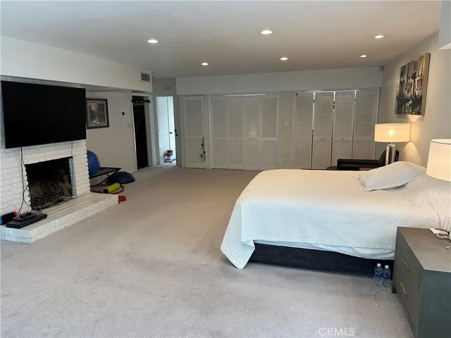a spacious bedroom with a bed a flat screen tv and a fireplace