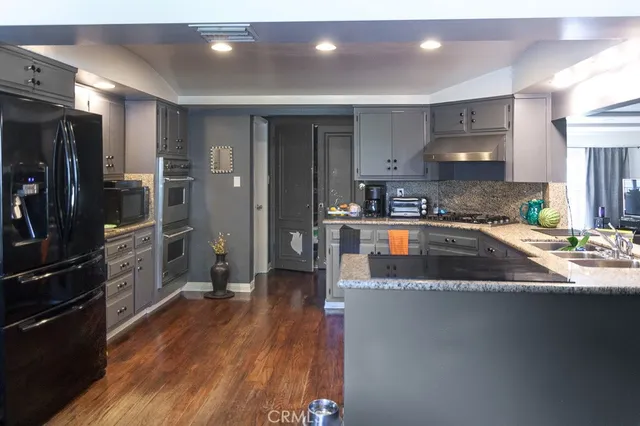 a kitchen with stainless steel appliances granite countertop a refrigerator a sink and a stove