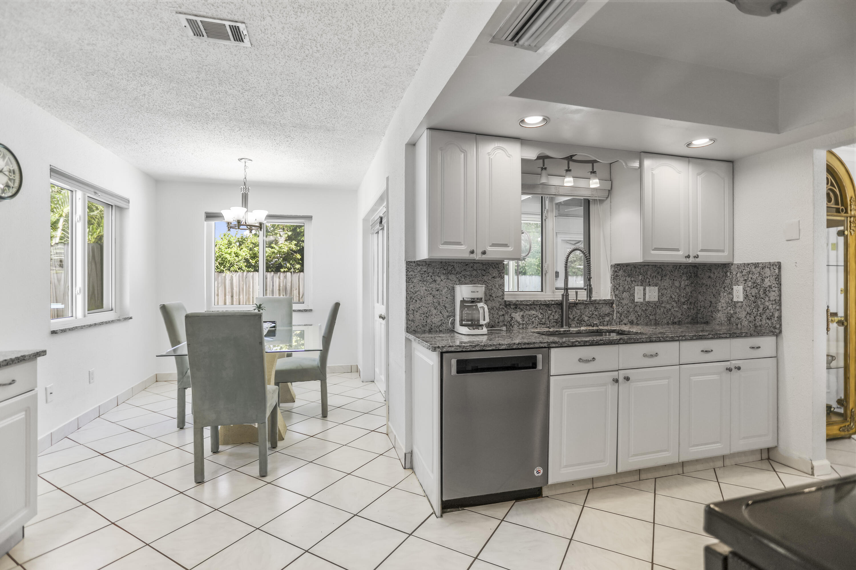 22682 Southwest 65th Avenue Boca Raton, FL 33428 - Photo 10 of 58 a kitchen with granite countertop white cabinets a dining table and chairs