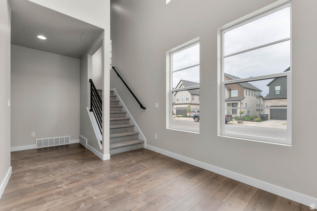 1567 North 3250 West Provo, UT 84601 - Photo 5 of 22 Open concept living area featuring wood-finish flooring, a carpeted staircase with a modern black railing, and multiple large windows