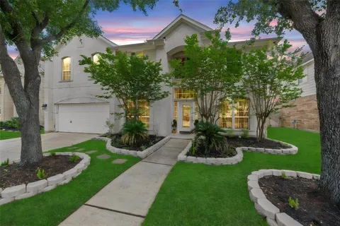 a view of a house with a yard and a large tree