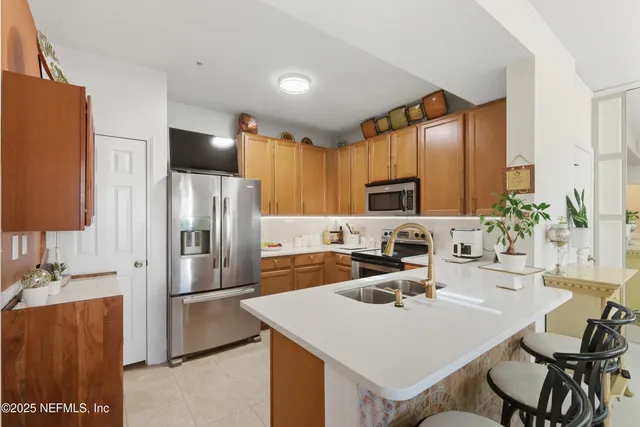 a kitchen with stainless steel appliances a sink a counter top space cabinets and a refrigerator