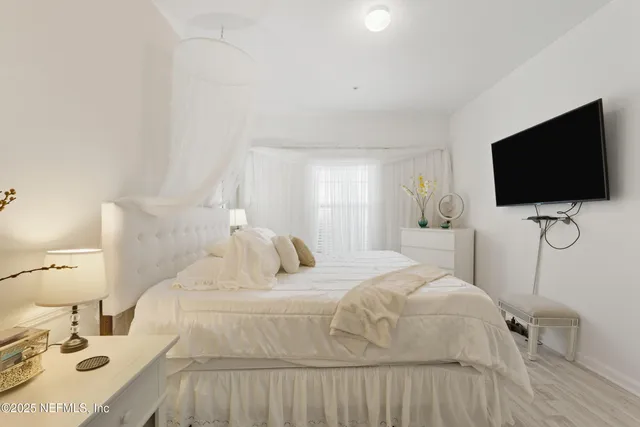 a bedroom with a bed and a flat tv screen on wall