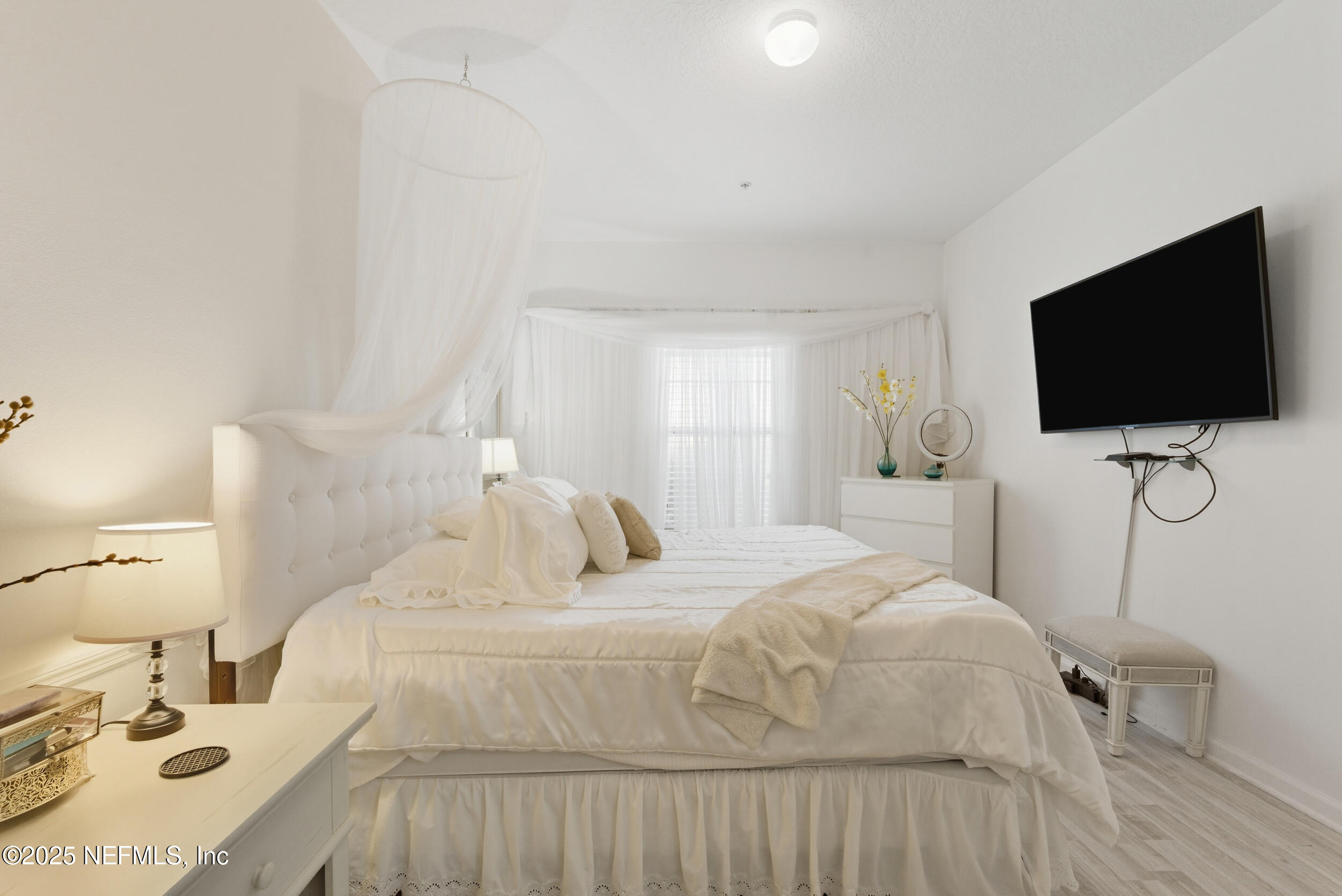 575 Oakleaf Plantation Parkway, Unit 1004 Orange Park, FL 32065 - Photo 7 of 22 a bedroom with a bed and a flat tv screen on wall