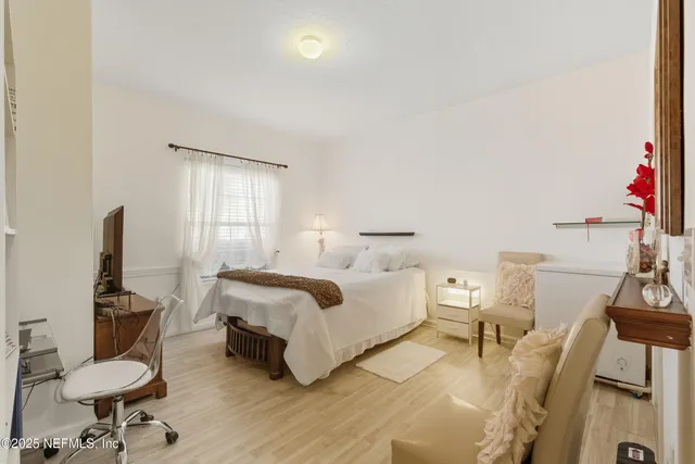 a spacious bedroom with a bed a couch and wooden floor