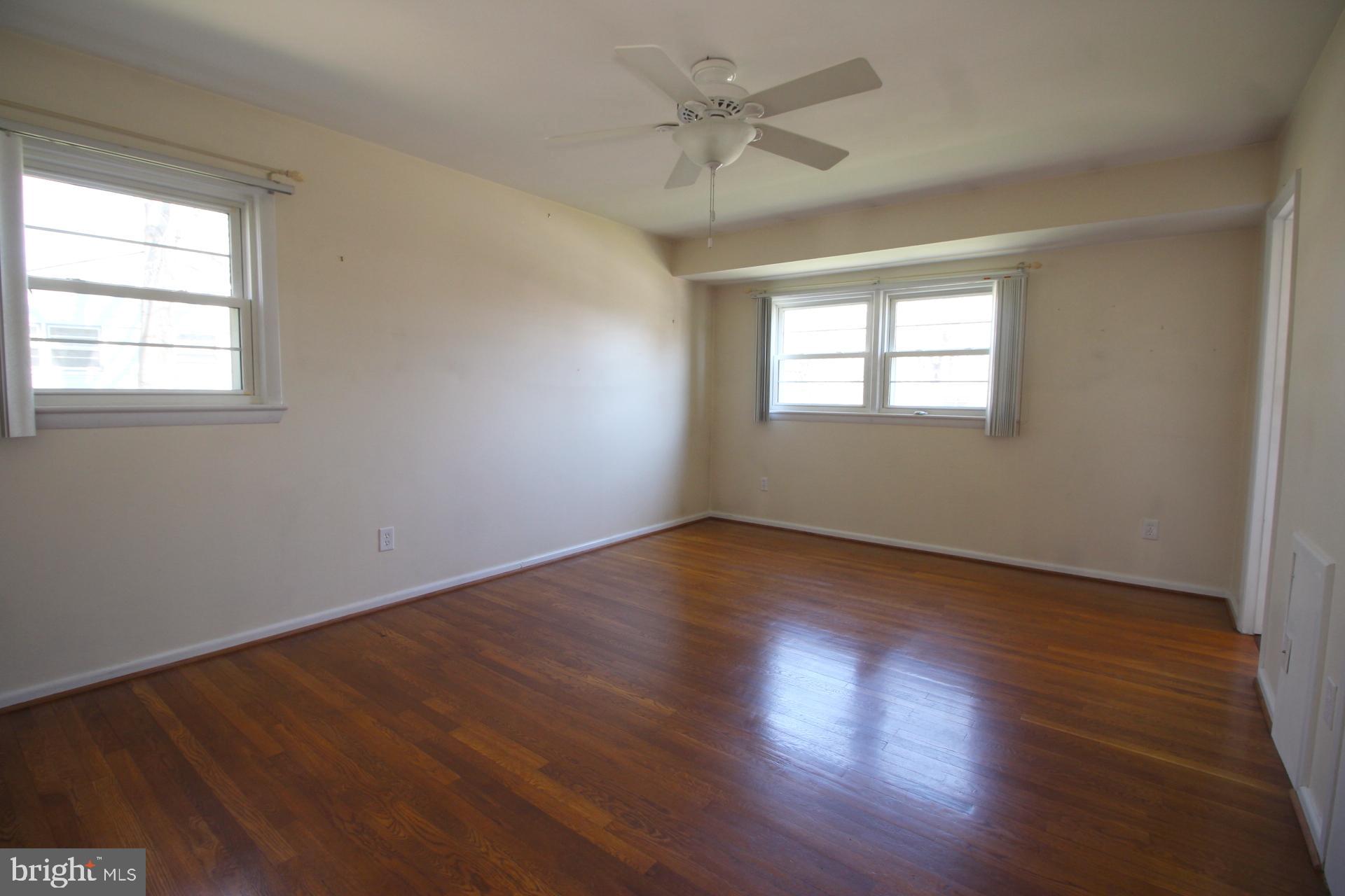 8504 Wagon Wheel Road Alexandria, VA 22309 - Photo 12 of 30 an empty room with wooden floor ceiling fan and windows
