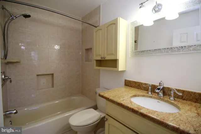 a bathroom with a granite countertop sink a toilet and shower