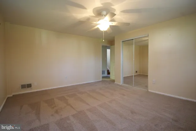 an empty room with a chandelier fan and windows