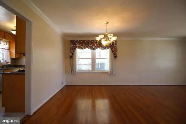 a view of a room with wooden floor chandelier and a window