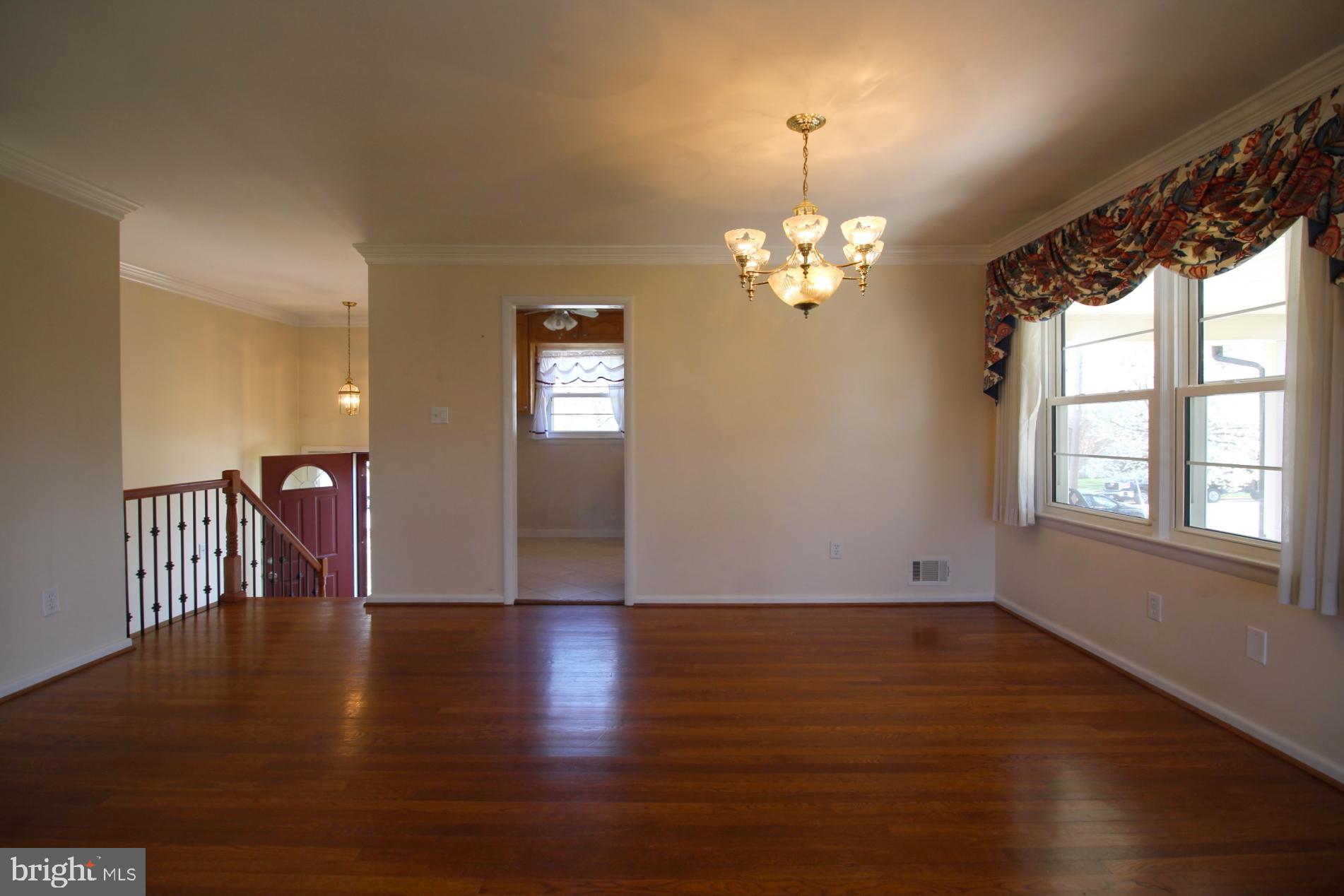 8504 Wagon Wheel Road Alexandria, VA 22309 - Photo 8 of 30 an empty room with wooden floor chandelier and windows