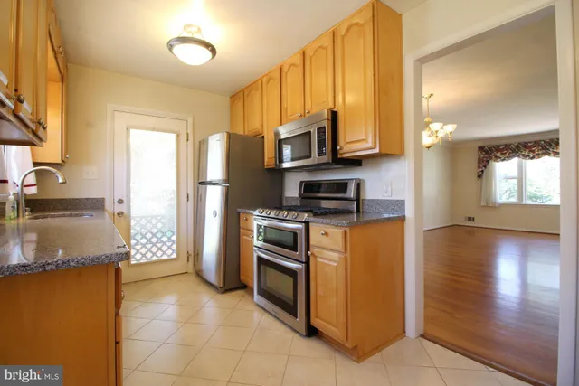 a kitchen with stainless steel appliances granite countertop a refrigerator a stove and a sink