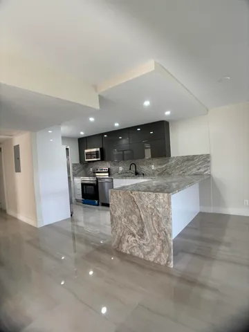 a large kitchen with kitchen island a stove a counter top space and cabinets
