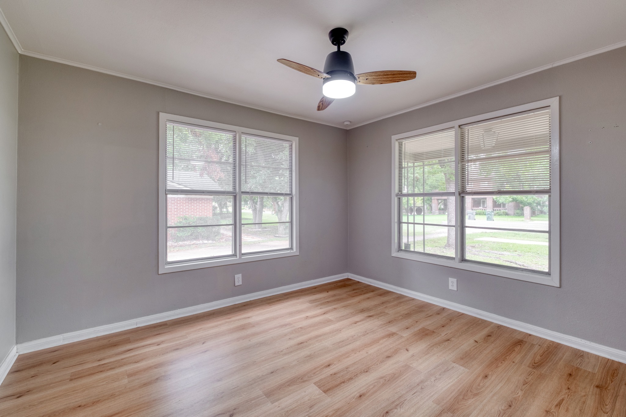 707 North Main Street Elgin, TX 78621 - Photo 8 of 21 Back bedroom with wood-look laminate flooring, ceiling fan, and windows for great natural light.