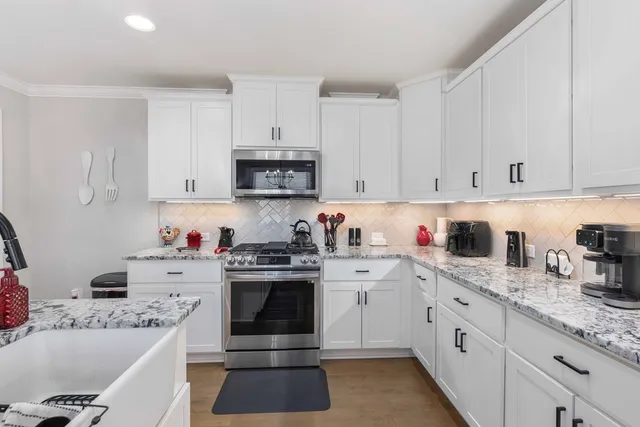a kitchen with stainless steel appliances granite countertop a sink stove and white cabinets