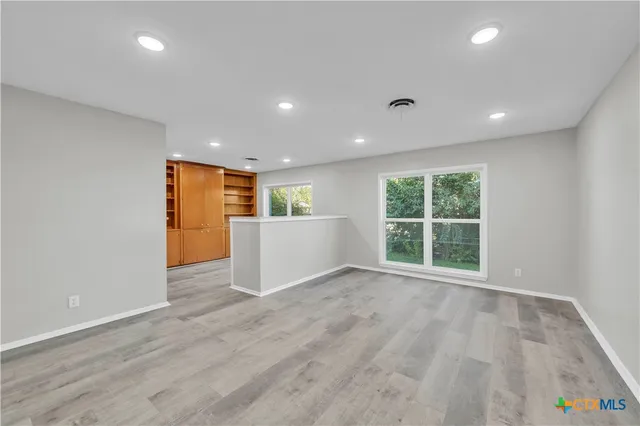 a view of an empty room with wooden floor and a window