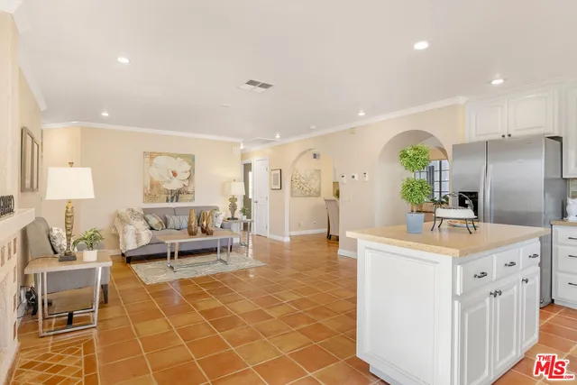 a kitchen with stainless steel appliances kitchen island granite countertop a refrigerator a sink a stove and white cabinets