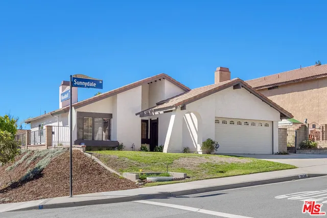 a view of a white house with a small yard and plants