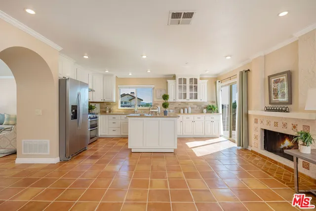 a living room with fireplace furniture and a view of kitchen